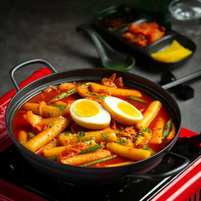 Cheesy Tokbokki korean traditional food on black board background. Lunch dish.